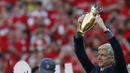 Pelatih Arsenal, Arsene Wenger, mengangkat trofi mini  saat perpisahan di Stadion Emirates (6/5/2018). Selama 22 tahun membesut Arsenal, Wenger telah mempersembahkan 17 gelar dan 704 Kemenangan. (AFP/Ian Kington)
