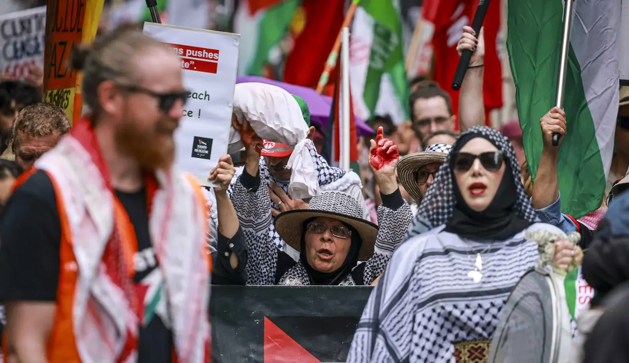 Kematian tidak langsung tersebut disebabkan oleh penyakit, kondisi medis kronis yang tidak tertangani, serta dampak runtuhnya sistem layanan kesehatan akibat perang. Tampak dalam foto, para demonstran pro-Palestina membawa bendera, spanduk, dan plakat saat mereka berbaris berunjuk rasa di jalanan kota Sydney, Australia, Minggu 22 Februari 2026. (DAVID GRAY/AFP)