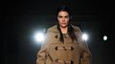 Kendall Jenner berjalan di catwalk saatmempersembahkan kreasi Prada selama Koleksi Wanita Musim Gugur-Musim Dingin 2023-2024 sebagai bagian dari Fashion Week di Milan pada 23 Februari 2023. Kendaall menambahkan beberapa inci ekstra tinggi ke bingkai patungnya dengan sepasang tumit gaya origami kuning keemasan yang unik, dihiasi dengan bunga. (AFP/Marco Bertorello)