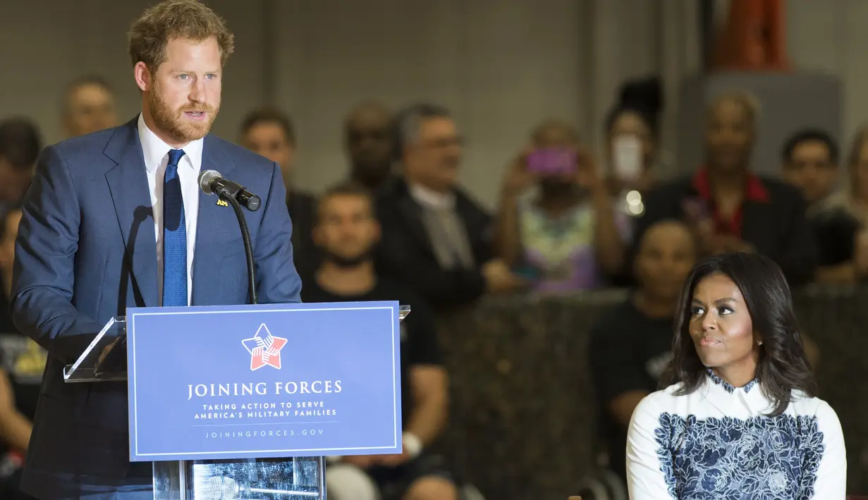 Michelle Obama mendengarkan Pangeran Harry berpidato saat menghadiri acara di Fort Belvoir, Virginia, Rabu (28/10). Pertemuan ini diadakan untuk mendukung pelaksanaan Invictus Games Orlando 2016 kepada para tentara yang terluka. (AFP PHOTO/SAUL Loeb)
