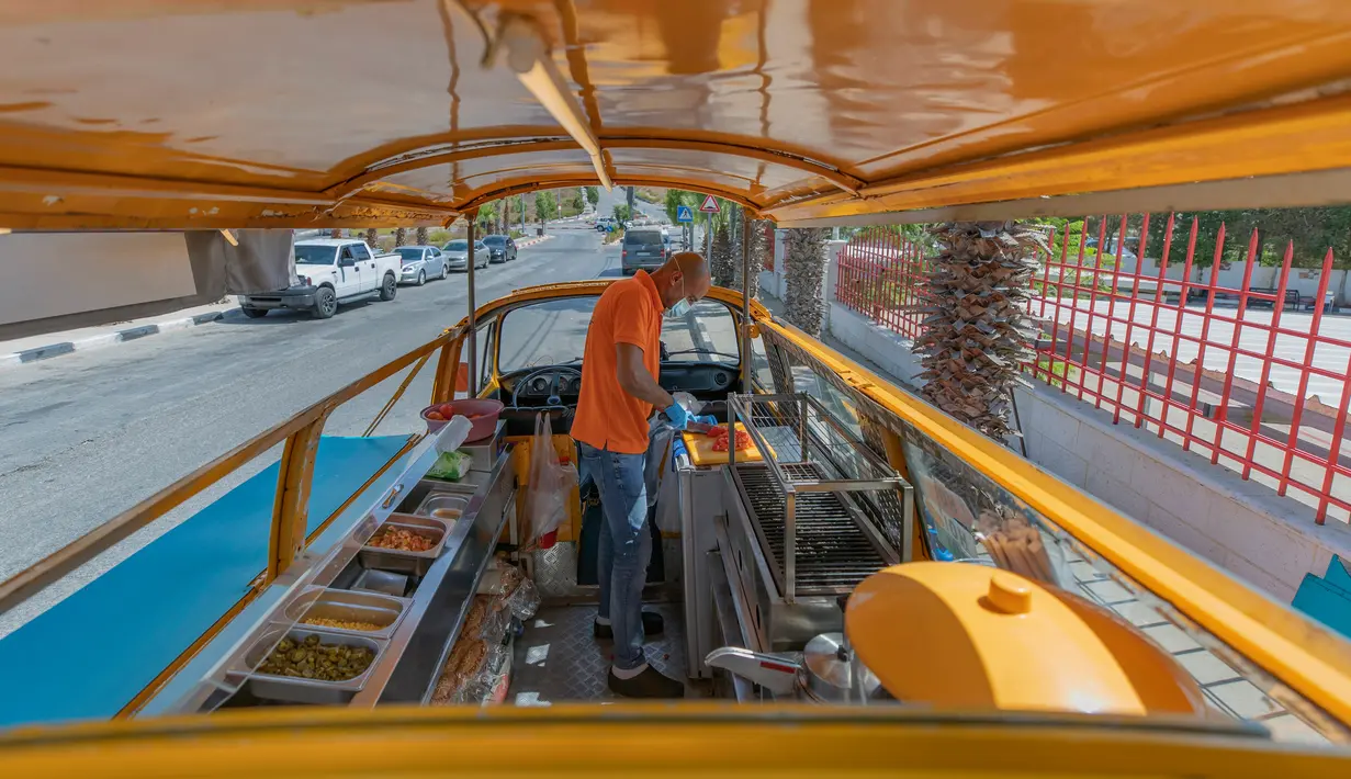 Emad Abdeljawwad menyiapkan hot dog untuk pelanggan dari mobil van yang telah diubah di Ramallah, Tepi Barat, 23 September 2020. Dengan sebagian besar restoran tutup karena pembatasan COVID-19, food truck memungkinkan pengusaha Palestina untuk menemukan cara tetap bekerja. (AP Photo/Nasser Nasser)