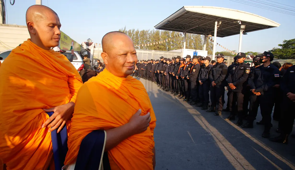  Dua Biksu berdiri di depan petugas saat melakukan penggeledahan Kuil Dhammakaya, Pathum Thani, Thailand (17/2). Kuil terbesar di Thailand ini digeledah untuk mencari biksu Phra Dhammachayo karena dakwaan pencucian uang. (AP Photo / Sakchai Lalit)