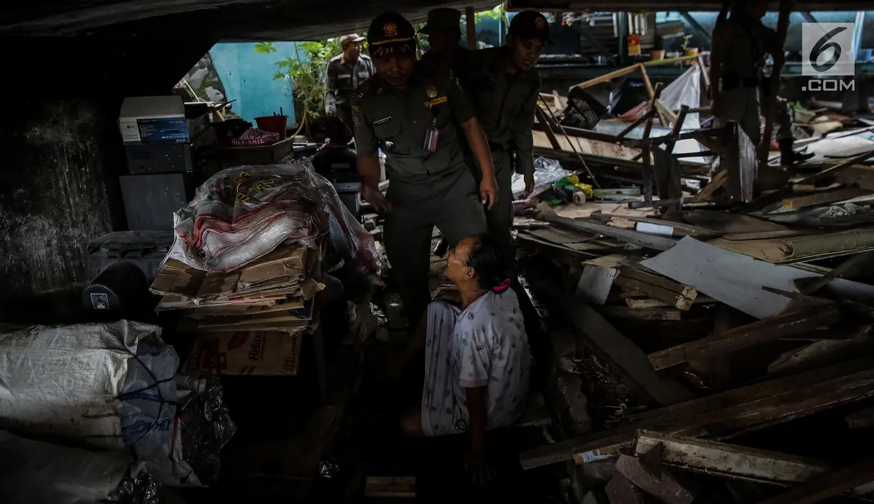 Seorang warga menolak bedengnya dibongkar oleh petugas Satpol PP di bawah kolong Tol Teluk Intan, Jakarta, Rabu (14/6). Petugas menggunakan alat berat untuk mempermudah dan mempercepat proses pembongkaran di lokasi tersebut. (Liputan6.com/Faizal Fanani)