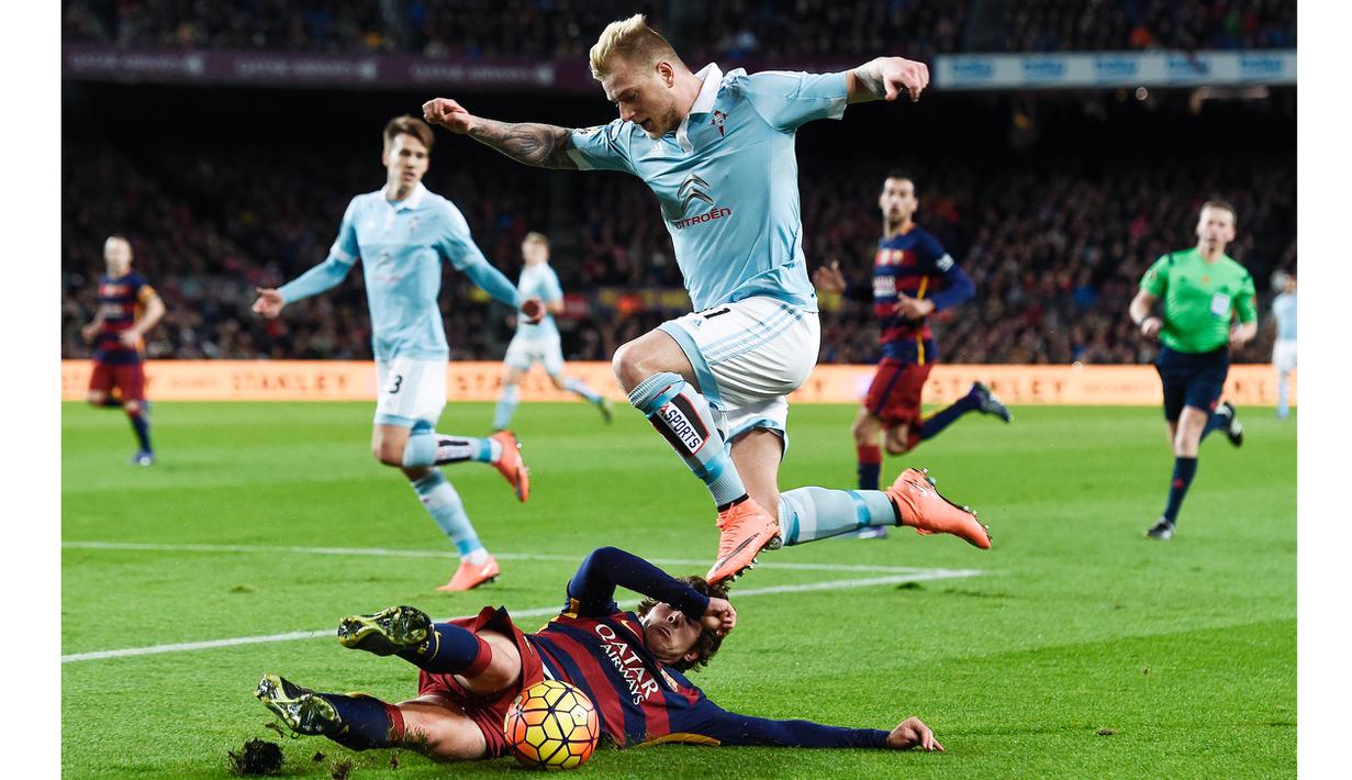 Pemain Celta, John Guidetti melompat menghindari hadangan pemain Barcelona, Sergi Roberto pada lanjutan La Liga Spanyol di Stadion Camp Nou, Barceloa, Senin (15/2/2016) dini hari WIB. Barcelona menang 6-1. (AFP/Josep Lago)
