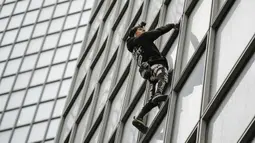 Pendaki Alain Robert atau French Spiderman memanjat Menara Total di kawasan bisnis La Defense, Paris, Prancis, Senin (13/1/2020). Alain hanya bermodalkan tangan kosong, sepasang sepatu panjat, dan sekantong kapur bubuk untuk membersihkan keringat. (Thomas SAMSON/AFP)