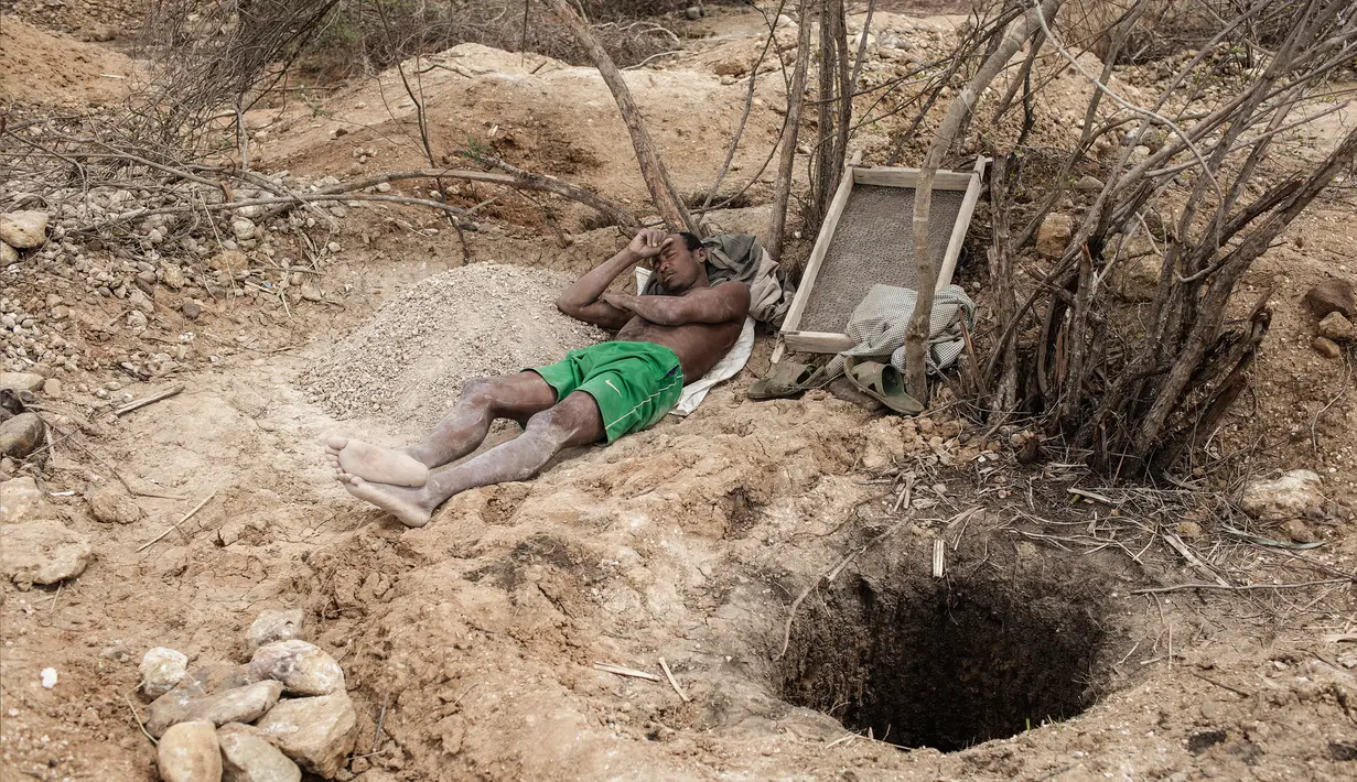 Seorang penambang beristirahat di sebelah lubang tambang safir di Sakaraha, Madagaskar. Pulau yang terletak di Samudra Hindia itu sudah menjadi salah satu produsen tambang batu mulia safir terbesar di dunia. (AFP Photo/Gianluigi Guercia)