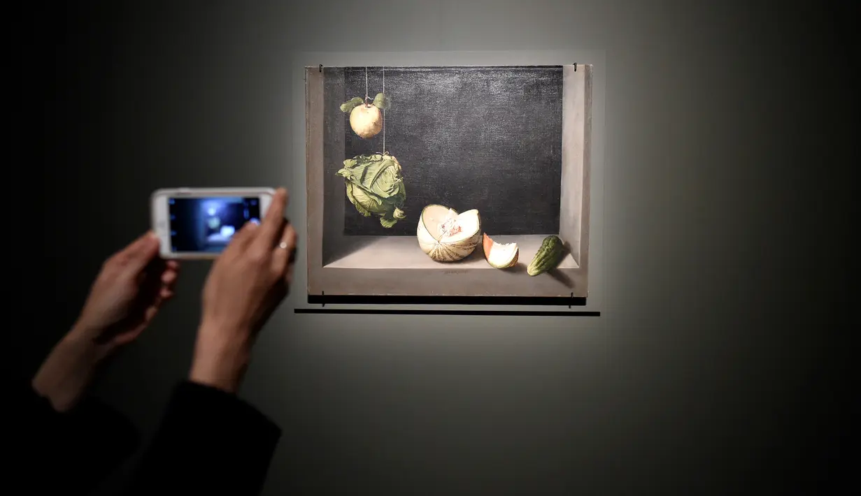 Seorang pengunjung mengambil gambar lukisan Quince, Cabbage, Melon and Cucumber (1602) karya pelukis Spanyol Juan Sanchez Cotan (1560-1627) saat pameran 'Spanish Still Life' di Pusat Seni Rupa BOZAR, Brussels, Belgia, Jumat (22/2). (AFP PHOTO/JOHN THYS)