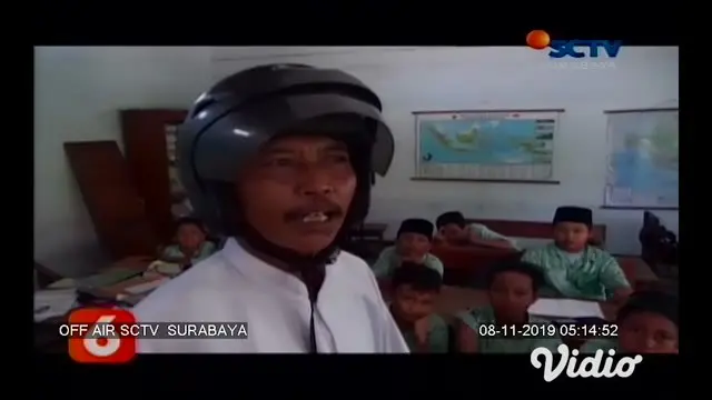 Seorang guru di SDN Kepuhkembeng 1 Jombang, Jawa Timur mengenakan helm saat mengajar. Diketahui ternyata bangunan sekolah tersebut sudah rusak parah.