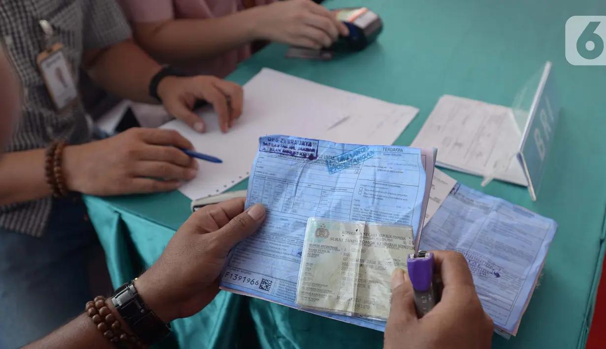 Pengendara menunjukkan bukti surat tilang jelang mengikuti sidang perkara pelanggaran lalu lintas di tempat E-Tilang pada Operasi Zebra Jaya 2019, Jakarta Barat, Jumat (1/11/2019). Operasi Zebra Jaya digelar hingga 5 November 2019. (merdeka.com/Imam Buhori)