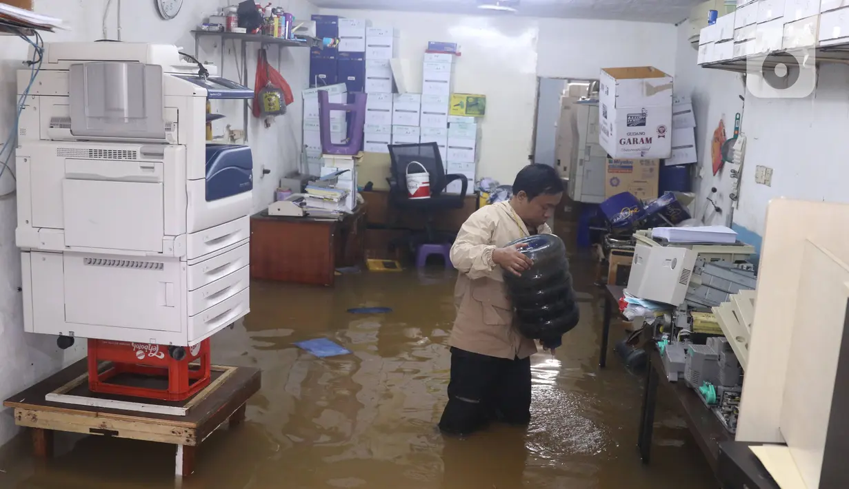 Seorang pria berada di dalam tokonya yang terendam banjir di Kawasan Bendungan Hilir (Benhil), Jakarta Pusat,  Selasa (25/2/2020). Salah satu wilayah terdampak banjir yakni kawasan Benhil hingga membuat akses jalan untuk sementara terputus.  (Liputan6.com/Angga Yuniar)
