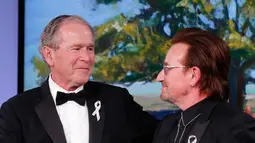 Presiden AS ke-43 George W. Bush berjabat tangan vokalis U2 Bono selama gala untuk Forum Kepemimpinan di Institut George W. Bush di Dallas, AS (19/4). Dalam acara ini Bush mempersembahkan Bono medali Distinguished Citizenship. (AP Photo/Brandon Wade)