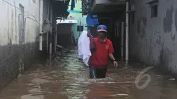 Warga melintasi banjir yang merendam Kampung Pulo, Jatinegara, Jakarta Timur, Selasa (10/2/2015). Sebagian wilayah Jakarta terendam banjir akibat hujan yang terus turun sejak Minggu (8/2) malam lalu. (Liputan6.com/Herman Zakharia)