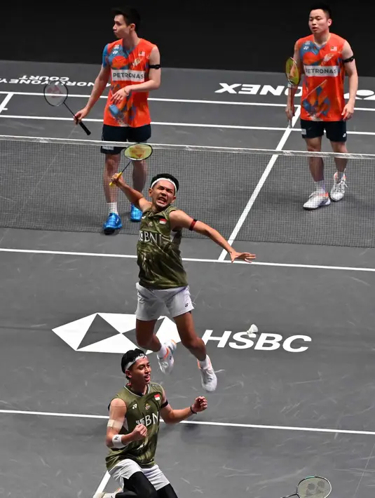 Pebulutangkis Ganda Putra Indonesia, Fajar Alfian (tengah) dan Muhammad Rian Ardianto (bawah) merayakan kemenangan atas Aaron Chia/Soh Wooi Yik dari Malaysia pada Final Kejuaraan Bulu Tangkis All England Terbuka di Utilita Arena di Birmingham, Inggris, pada 17 Maret 2024. (JUSTIN TALLIS/AFP)