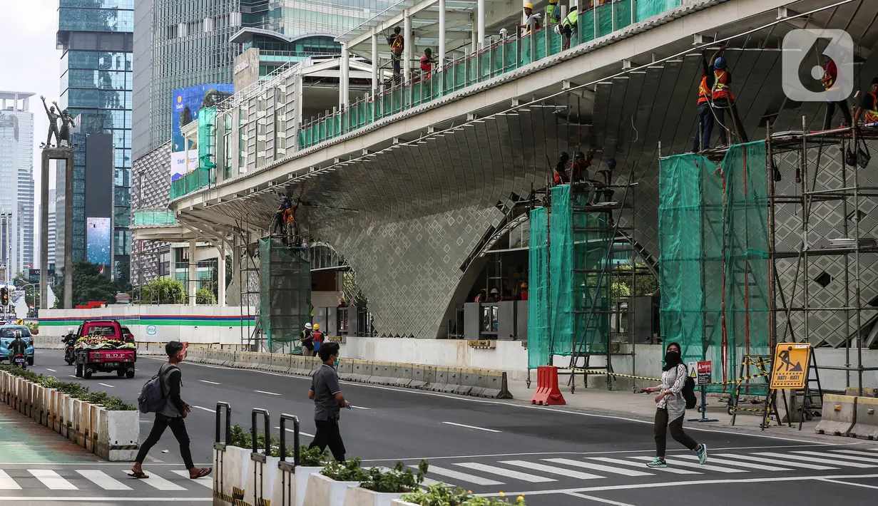 Pejalan kaki menyeberang dekat proyek pembangunan Halte TransJakarta di Hotel Indonesia, Jakarta, Jumat (30/9/2022).  Sejarawan JJ Rizal menyarankan agar PT Transjakarta dapat membangun halte yang ramah kawasan bersejarah. (Liputan6.com/Johan Tallo)