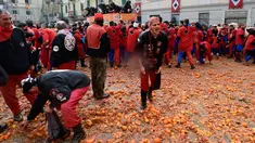 Peserta berjalan di atas tumpukan jeruk yang hancur pada festival "Battaglia delle Arance" (Perang Jeruk) di sebuah kota kecil di Provinsi Turin, Italia, Minggu (11/2). Tradisi melempar jeruk dilakukan selama tiga hari pada Februari. (MIGUEL MEDINA/AFP)