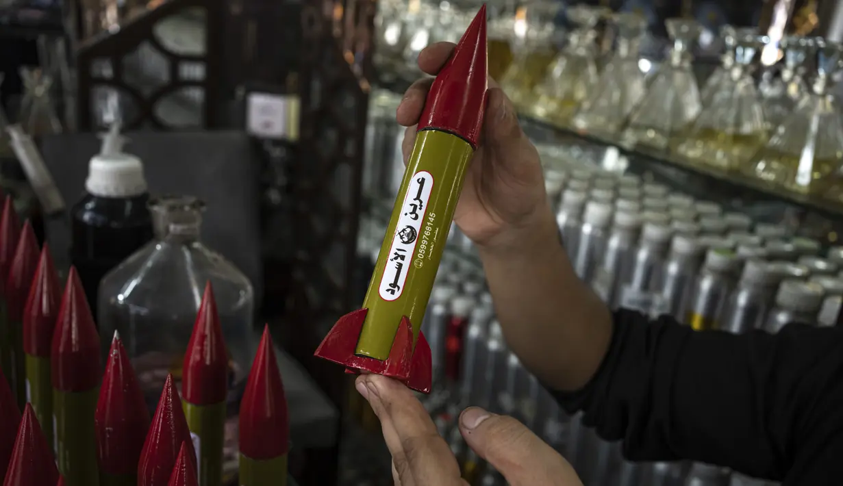 Belal Abu Saraya berpose dengan wadah parfum yang melambangkan roket yang digunakan untuk melawan Israel di sebuah toko parfum yang digunakan untuk melawan Israel dalam konflik masa lalu di tokonya di Kota Gaza pada Kamis, 5 Oktober 2023. (AP Photo/Fatima Shbair)