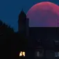 Bulan tampak berwarna merah darah saat terjadinya fenomena gerhana bulan total  di Bernkastel-Kues, Jerman, Jumat (27/7). Gerhana bulan yang terlama pada abad ini dapat disaksikan di seluruh dunia dengan mata telanjang. (Harald Tittel/dpa via AP)