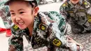 Ekspresi anak-anak saat merangkak dalam mengikuti simulasi latihan militer di sebuah taman kanak-kanak di provinsi Henan, China (30/5). (AFP)