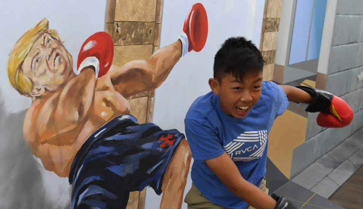 Seorang bocah berpose sedang memukul Presiden AS Donald Trump di Museum of Illusions di Hollywood, California (27/3). Di museum ini, pengunjung bebas bergaya dengan lukisan 3D tersebut untuk menghasilkan foto unik dan tidak biasa. (AFP Photo/Mark Ralston)