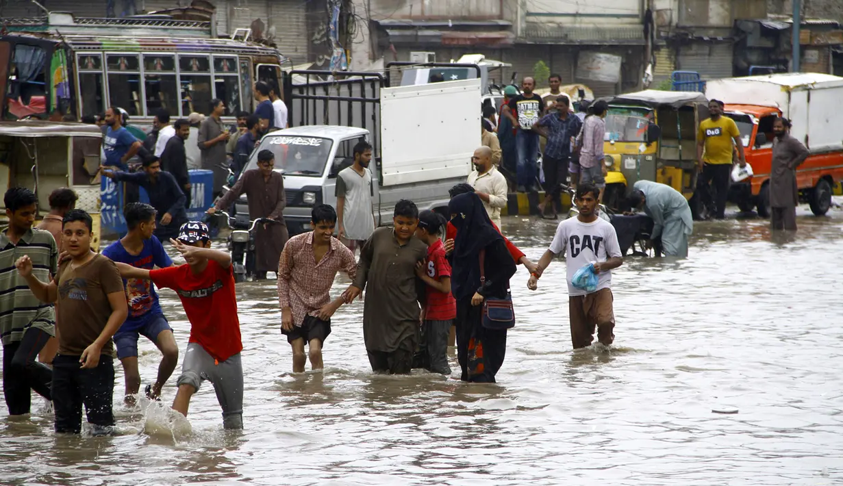 Orang-orang berjalan menembus genangan air banjir setelah hujan monsun mengguyur deras di Kota Karachi, Pakistan, 25 Agustus 2020. Hujan monsun menelan empat korban jiwa di kota tersebut pada Selasa (25/8/2020), sementara banyak orang lainnya mengalami luka-luka. (Xinhua/Str)