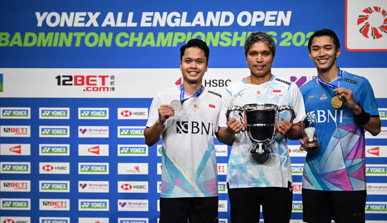 Peraih medali perak Anthony Sinisuka Ginting (kiri) dan peraih medali emas Jonatan Christie (kanan) merayakannya bersama pelatih mereka, Hendri Kurniawan Saputra di podium setelah bertanding di Final Tunggal Putra Kejuaraan Bulutangkis Terbuka All England di Utilita Arena, Birmingham, Inggris tengah, pada 17 Maret 2024. (JUSTIN TALLIS/AFP)