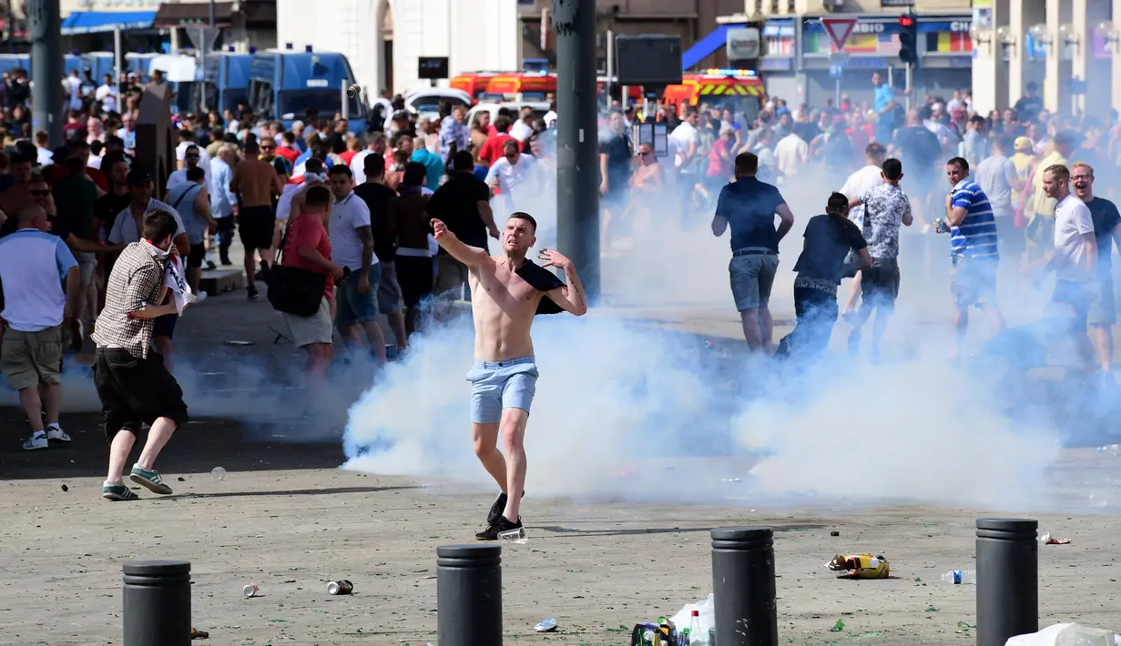 Fans Inggris melempar kembali gas air mata saat bentrokan antara fans Inggris dan polisi di kota Marseille, Prancis (11/6/2016). Bentrok terjadi menjelang pertandingan sepak bola Euro 2016 antara Inggris dan Rusia. (AFP Photo/Leon Neal)