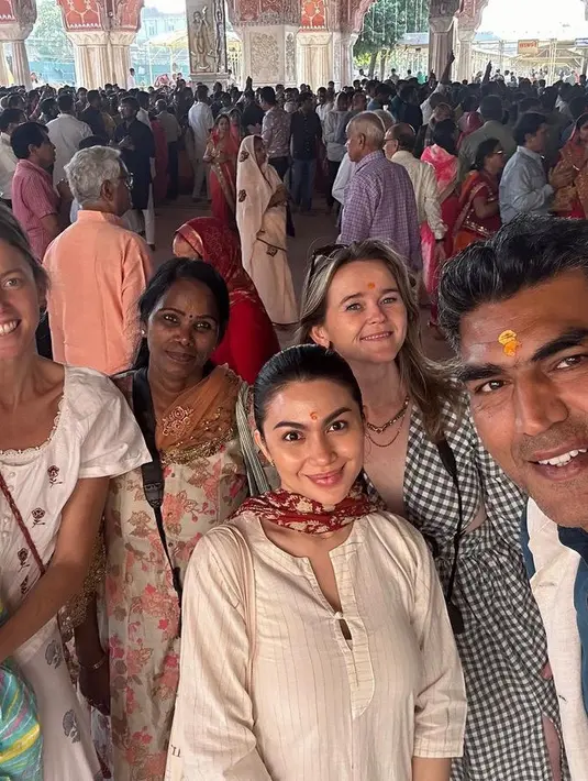 Ariel Tatum tampil sederhana mengenakan baju waena putih motif bergaris lengan 3/4 dengan kancing depan. Dipadukan syal merah yang melingkar di lehernya. [@arieltatum]