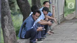 Sopir taksi berbincang tanpa mengenakan masker saat menunggu penumpang di kawasan Cawang, Jakarta, Rabu (8/4/2020). Organisasi Kesehatan Dunia (WHO) telah merekomendasikan agar menggunakan masker saat berada di tempat umum demi memutus mata rantai penyebaran virus Corona. (merdeka.com/Iqbal Nugroho)