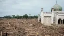 Akses menuju bangunan dan asrama hanya bisa dilalui dengan memanjat tumpukan kayu. Tampak dalam foto, para pria berjalan di atas tumpukan pohon tumbang yang tersapu banjir bandang sekitar tiga minggu lalu di Pesantren Darul Mukhlisin dan masjid yang terhubung dengan pesantren tersebut di Aceh Tamiang, pada Minggu 14 Desember 2025. (Yasuyoshi CHIBA/AFP)