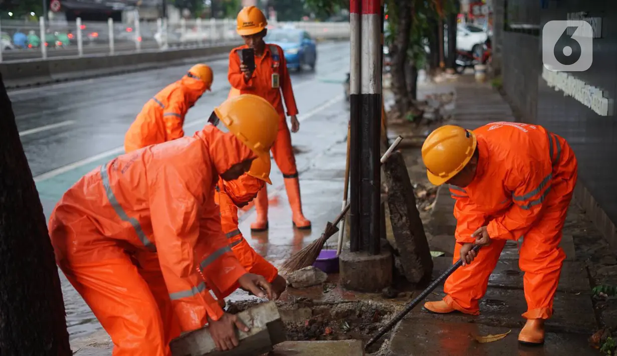 Petugas PPSU membersihkan saluran air yang tersumbat di Jalan Mampang Prapatan Raya, Jakarta, Rabu (11/12/2019). Hal tersebut dilakukan guna mengurangi genangan air yang terjadi di sejumlah sudut Ibukota setiap kali hujan deras mengguyur Jakarta. (Liputan6.com/Immanuel Antonius)