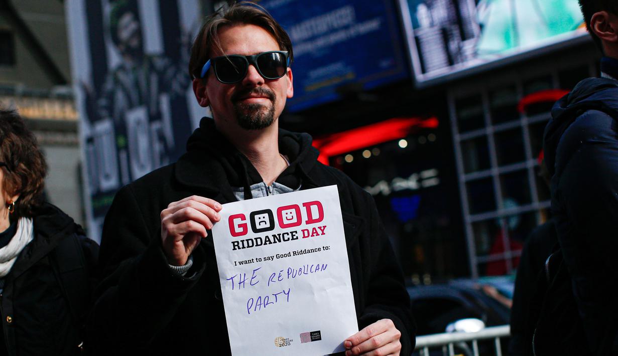 Seorang pria memegang kertas bertuliskan "Partai Republik" selama kegiatan Good Riddance Day di Times Square, New York, 28 Desember 2019. Secara simbolis, mereka membersihkan kenangan yang tidak menyenangkan selama tahun 2019 dan mencetuskan harapan mereka untuk tahun yang baru (Kena Betancur / AFP)