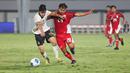 Pemain Timnas Indonesia U-17, I Komang Semadi berduel dengan pemain China U-17, Li Junpeng dalam pertandingan uji coba internasional di Indomilk Arena, Tangerang, pada Rabu (11/2/2026) malam WIB. (Bola.com/Abdul Aziz)