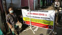 Seorang pria menjaga akses masuk zona merah COVID-19 di Kelurahan Petogogan RT 006 RW 003, Jakarta, Selasa (22/6/2021). Pemerintah Provinsi DKI Jakarta memperbarui data zona pengendalian virus Corona di tingkat rukun tetangga (RT) se-Ibu Kota.  (Liputan6.com/Faizal Fanani)