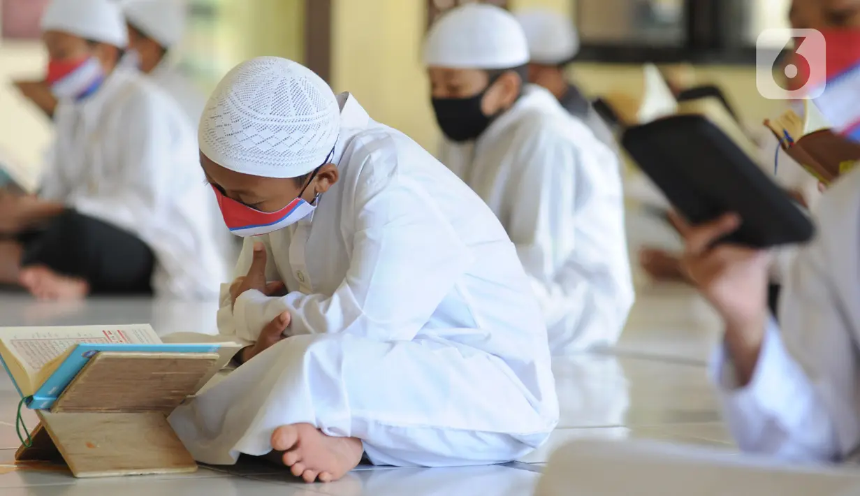 Sejumlah santri berusia belasan tahun membaca Al quran atau tadarus bersama-sama dengan menerapkan jaga jarak di Masjid Daarul Qu'ran Pesantren Al Kautsar, Cibinong, Bogor, Kamis (7/5/2020). Kegiatan Khatam Al quran tersebut dilakukan rutin di setiap bulan Ramadan. (merdeka.com/Arie Basuki)
