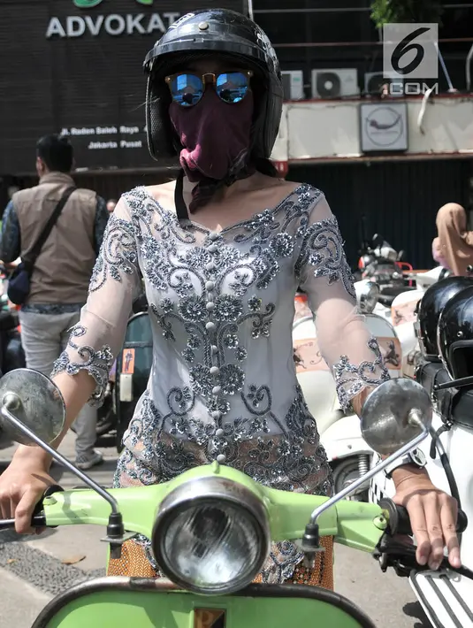 Anggota komunitas Vespa se-Jabodetabek berpose di atas kendaraannya di sela konvoi dalam rangka memperingati Hari Kartini di Jakarta, Minggu (21/4). Dalam konvoi ini para pengendara vespa mengenakan kebaya bagi perempuan dan batik serta lurik bagi laki-laki. (merdeka.com/Iqbal Nugroho)