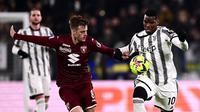 Pemain Juventus, Paul Pogba (kanan) berebut bola dengan pemain Torino, Jacopo Segre pada laga lanjutan Liga Italia 2022/2023 yang berlangsung di Allianz Stadium, 28 Februari 2023. Ini merupakan laga debut kedua bagi Pogba bersama Juventus. (AFP/Marco Bertorello)