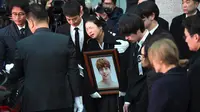 Sedangkan kakak dari Jonghyun tak kuasa menahan tangis. Ia terlihat memeluk foto mendiang adiknya. (JUNG Yeon-Je/AFP)