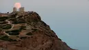 Pemandangan bulan purnama hampir penuh yang menampakkan diri di langit Kuil Poseidon kuno di Cape Sounion, sekitar 70 kilometer sebelah tenggara Athena, Yunani (2/8/2020). (Xinhua/Marios Lolos)