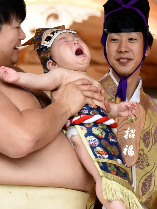 Seorang bayi menangis saat digendong pesumo selama Festival Nakizumo atau kontes bayi menangis di kuil Kamegaike-Hachiman, Jepang, Minggu (14/5). Festival tradisional ini dipercaya bisa membuat bayi besar dengan cepat dan lebih sehat. (Toru YAMANAKA/AFP)