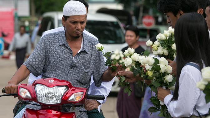 Umat Buddha Myanmar membagikan mawar putih kepada umat Islam yang akan melaksanakan salat Id pada perayaaan Idul Fitri di kota Than Lyin, pinggiran Yangon, Rabu (5/6/2019). Relawan berbaris di luar masjid dan memberikan bunga itu kepada jemaah yang merayakan Idul Fitri. (Sai Aung MAIN/AFP)