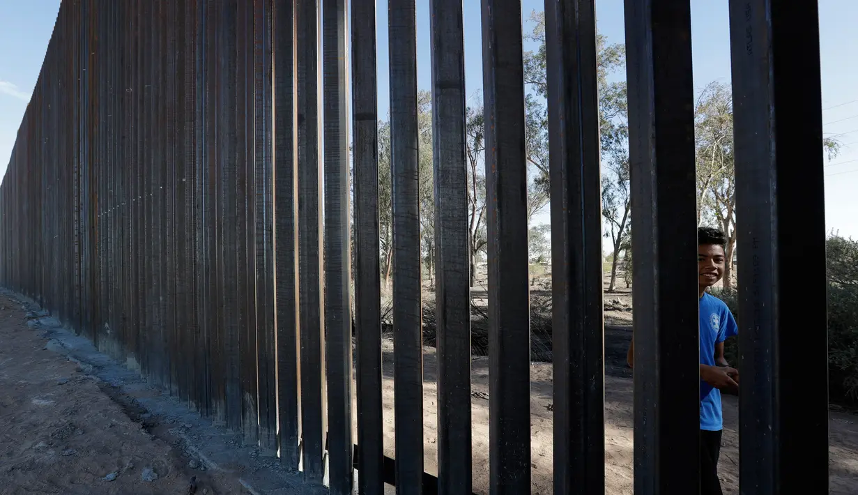 Seorang anak laki-laki melihat-lihat pagar perbatasan Amerika Serikat (AS) dengan Meksiko di Calexico, California, AS, Minggu (5/3). Kontrak kerja pembuatan pembatas di lokasi itu didapat di era kepemimpinan Presiden Donald Trump.(AP Photo/Gregory Bull)