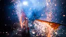 Seorang pria menahan percikan kembang api yang diarahkan ke tubuhnya saat ritual "eating flowers" di Xiaohu, Tiongkok (8/3). Ritual ini selalu digelar setiap tahunnya. (AFP Photo/Johannes Eisele)
