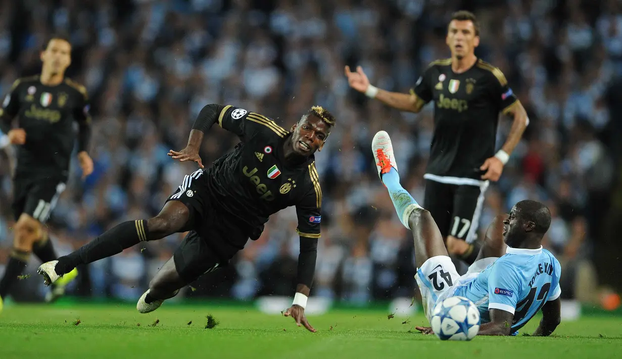 Pemain Manchester City, Yaya Toure (kanan) terjatuh setelah berebut bola dengan pemain Juventus FC, Paul Pogba (kiri) pada laga UEFA Champions League grup D di Stadion Etihad, Manchester, (15/12/2015). Manchester City Kalah 1-2. (EPA/Peter Powell).