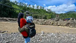 Terputusnya akses jalan dan jembatan membuat warga Kecamatan Ketol bertahan hidup menghadapi keterisolasian dengan menggunakan tali sling untuk melintasi sungai demi menjalani aktivitas sehari-hari. Tampak dalam foto, warga menggunakan tali untuk menyeberangi sungai setelah banjir bandang yang menghancurkan desa-desa di sekitarnya di Ketol, provinsi Aceh, pada Selasa 6 Januari 2026. (CHAIDEER MAHYUDDIN/AFP)