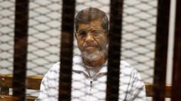 Mantan Presiden Mesir Mohammed Morsi duduk dalam penjara terdakwa di saat menjalani sidang di Akademi Kepolisian Nasional, Kairo, Mesir, 8 Mei 2019. Mohammed Morsi meninggal dalam sidang pengadilan pada Senin 17 Juni 2019 waktu setempat. (AP Photo/Tarek el-Gabbas, File)