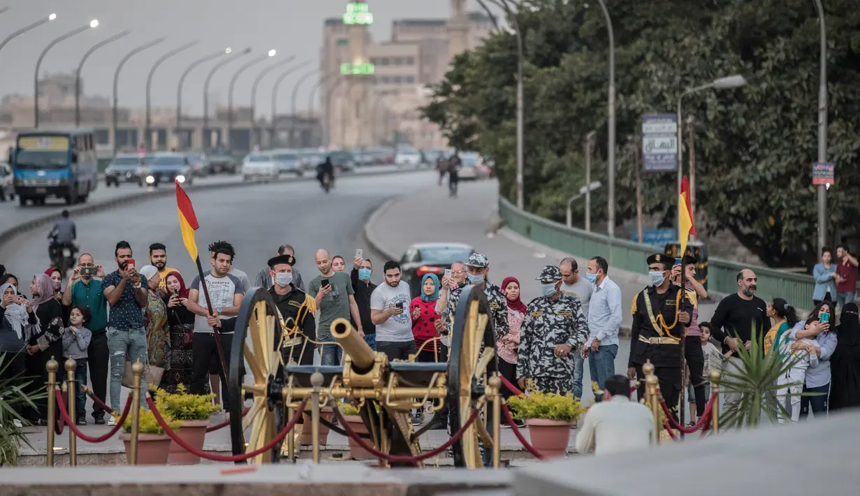 Pasukan keamanan Mesir mengenakan masker bersiap untuk menembakkan meriam Ramadan untuk menandai berbuka puasa di distrik Giza, Kairo, Senin (11/5/2020). Meriam tradisional tersebut selalu digunakan pada bulan suci Ramadan untuk mengumumkan  iftar atau waktu berbuka puasa. (Khaled DESOUKI / AFP)