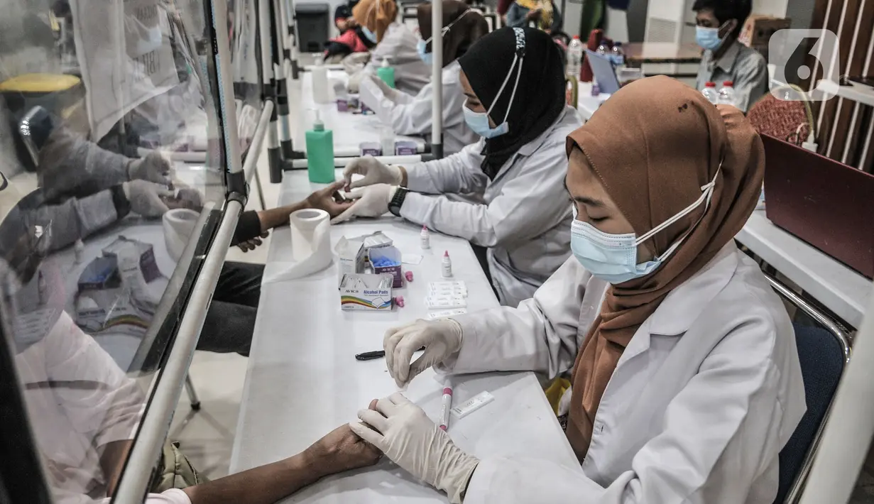 Petugas medis melakukan rapid test COVID-19 terhadap calon penumpang di Stasiun Pasar Senen, Jakarta, Senin (26/10/2020). Jumlah penumpang kereta jarak jauh mengalami lonjakan sehingga terjadi antrean panjang rapid test yang menjadi syarat wajib pengguna jasa KAI. (merdeka.com/Iqbal S. Nugroho)