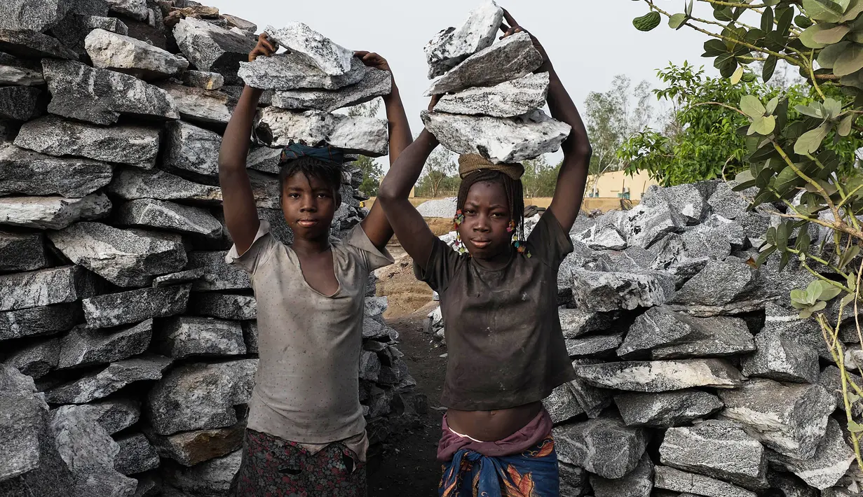  Bocah perempuan mengangkat bongkahan batu saat bekerja di sebuah tambang di Ouagadougou, Burkina Faso, 21 Desember 2015. 12 Juni ditetapkan sebagai Hari Penentangan Pekerja Anak Sedunia. (NABILA EL Hadad / AFP)