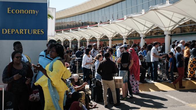 Penumpang berkumpul di luar terminal keberangkatan Kenya Airways  setelah pemogokan pekerja maskapai di Bandara Internasional Jomo Kenyatta, Nairobi, Rabu (6/3). Di dalam bandara, pengunjuk rasa berhadapan dengan polisi antihuru-hara (Yasuyoshi CHIBA/AFP)