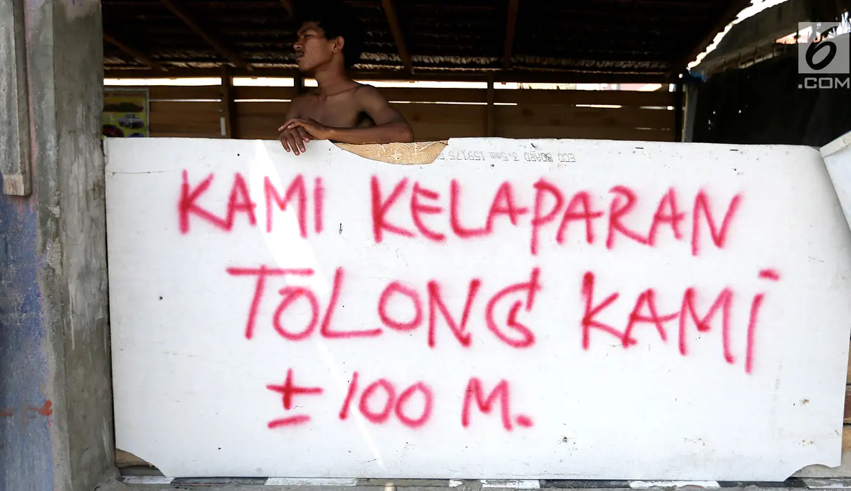 Warga bediri di posko dengan pesan bertuliskan Kami Kelaparan Tolong Kami pasca gempa bumi dan tsunami di Jalan Trans Sulawesi, Palu, Sulawesi Tengah, Kamis (4/10). (Liputan6.com/Fery Pradolo)